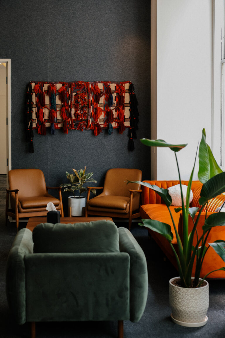 Lounge with a dark feature wall, leather chairs and large plants