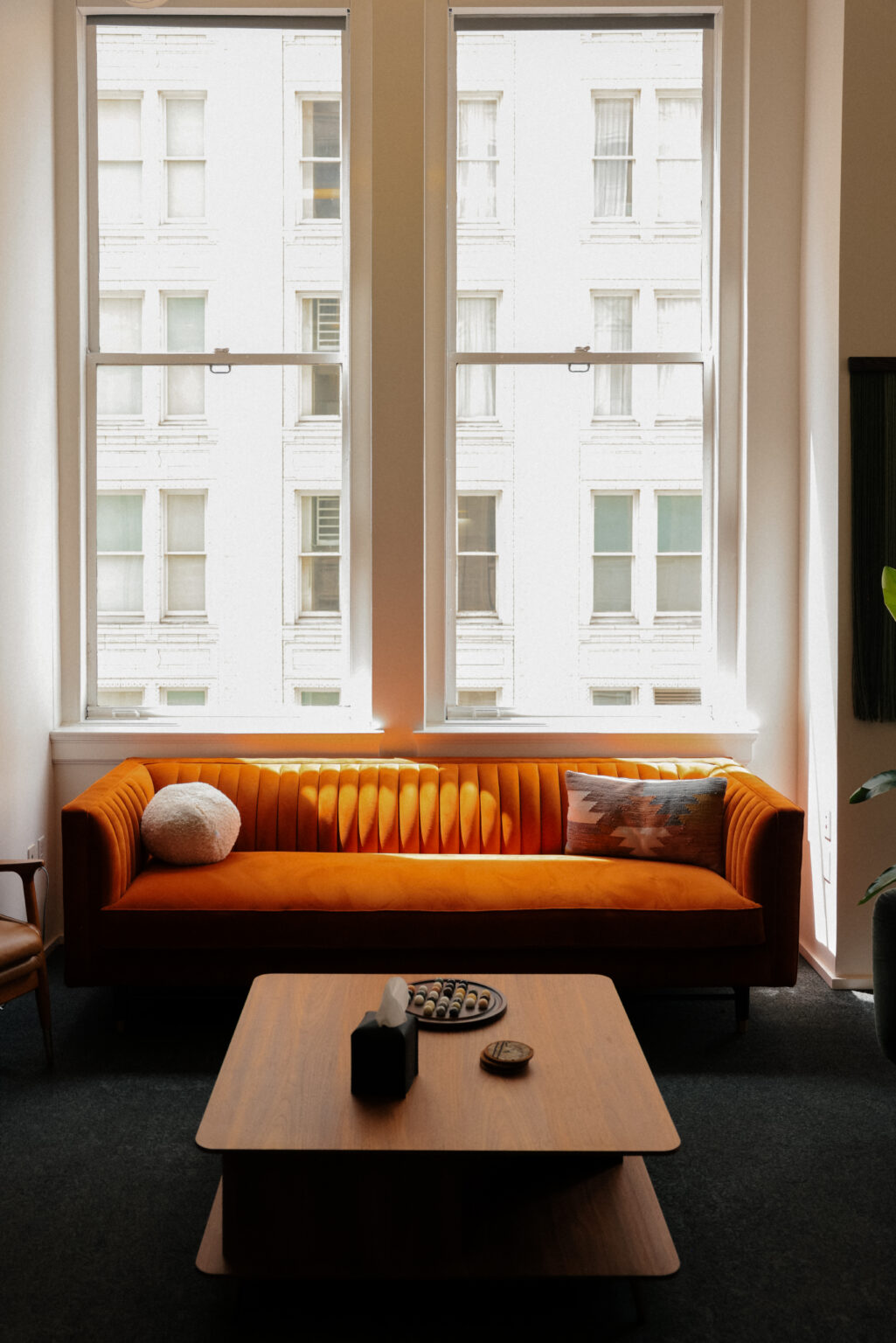 A long tan sofa beneath tall windows in a warm, light-filled living room