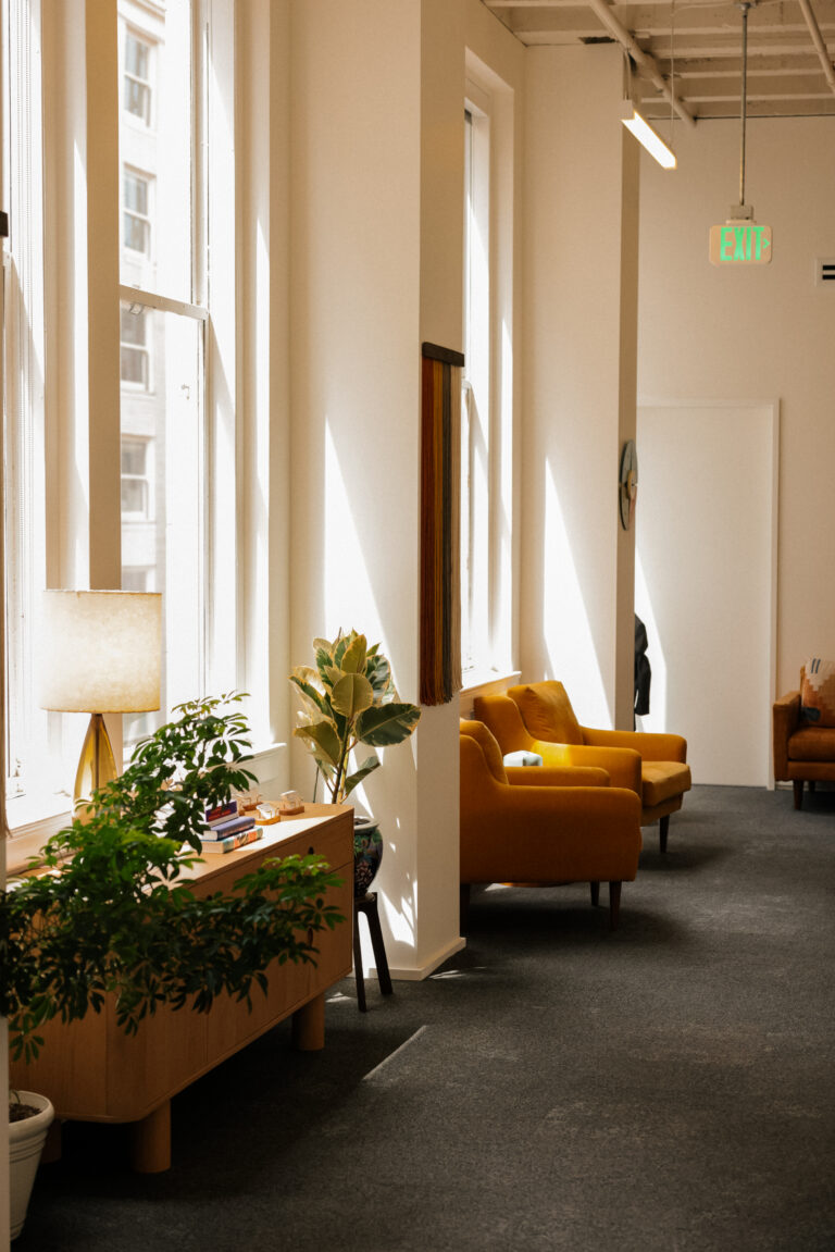 Sunlit living room with a caramel leather armchair, linen curtains and layered plants